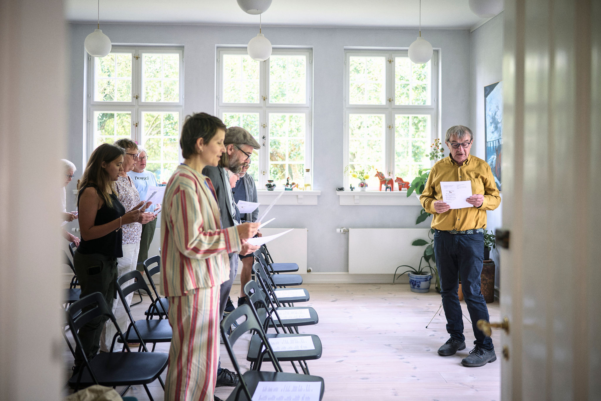 Deltagere samlet med sangark i et lyst lokale